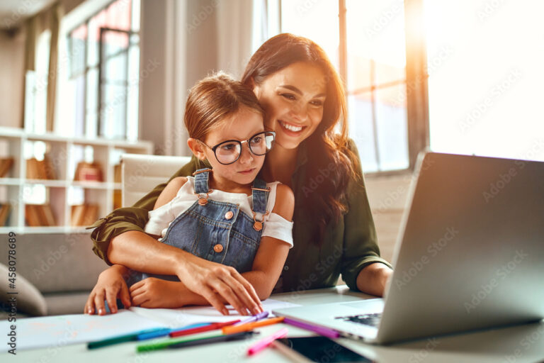 Business woman and mom working with her little daughter at a laptop. Freelance, work from home.